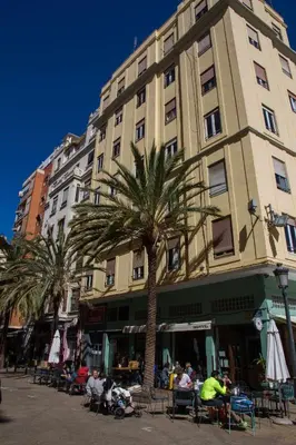 a tall building with palm trees in front of it at Russafa Youth Hostel in Valencia