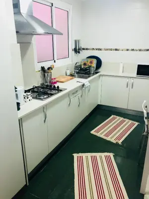 a kitchen with white cabinets and a green floor at Mar & City Apartment in Valencia