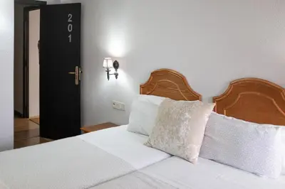 a bedroom with a bed with a wooden headboard and pillows at Hostal Victoria in Altura