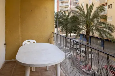a white table and chairs on a balcony with palm trees at Mar y Montaña, 2º-18 in Cullera