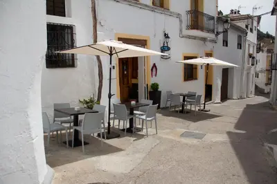 two tables and chairs with umbrellas in an alley at Hostal El Pozo in Chulilla