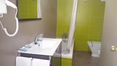 a bathroom with a sink and a shower and a toilet at Hotel Avenida in Requena