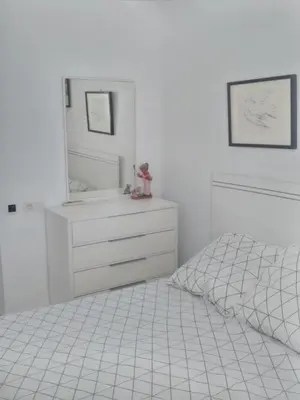 a white bedroom with a bed and a dresser at Atico Duplex 1ª in Xilxes