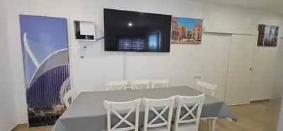 a table with white chairs and a television on a wall at A123 ViviendaTuristicaValencia Grandes Grupos in Valencia