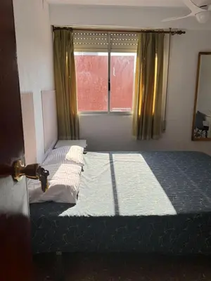 a bedroom with a bed and a window with curtains at Casa De La Luz in Valencia
