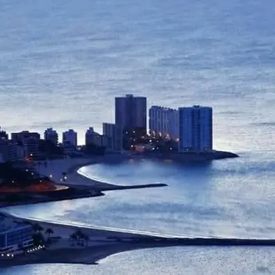 a view of a city in the ocean at night at apartamento junto al mar in Cullera