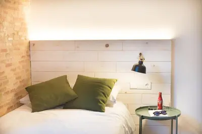 a bed with green pillows and a glass table at Casa del Patriarca in Valencia