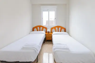 two beds in a room with a desk and a window at Turia in Tavernes de Valldigna