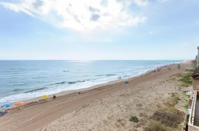 a beach with a group of people and the ocean at Turia in Tavernes de Valldigna