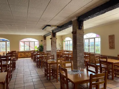 a restaurant with wooden tables and chairs and windows at Area de servicio El Rebollar in Requena