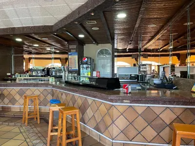 a restaurant with a bar with stools at a counter at Area de servicio El Rebollar in Requena