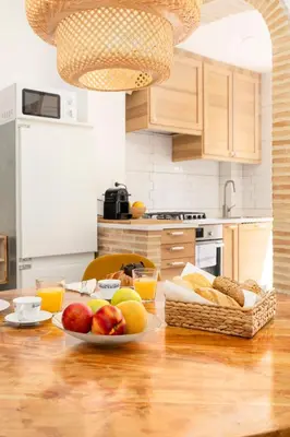 a kitchen with a table with plates of fruit and bread at Travel Habitat Cabanyal in Valencia