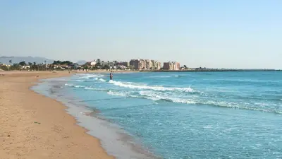 a beach with a person walking in the waves at Disfruta de unos días en la playa ¡Y mucho más! in Burriana