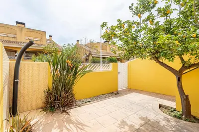 a yellow fence with a tree in a courtyard at Family-Friendly Beach House ideal for Holidays & Workers at Beach Sagunto Valencia in Sagunto