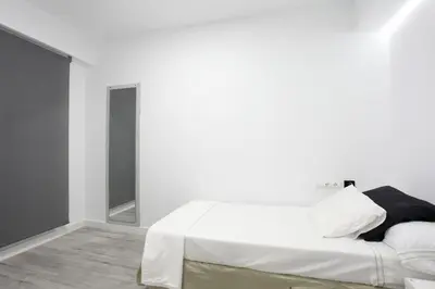a white bedroom with a bed and a mirror at 5 SENSES in Valencia