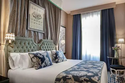 a bedroom with a bed with blue and white pillows at NH Collection Colón Valencia in Valencia