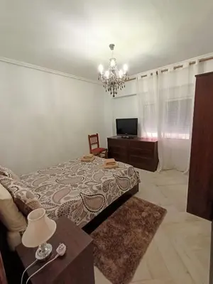 a bedroom with a bed and a table and a chandelier at el piso perfecto in Puerto de Sagunto