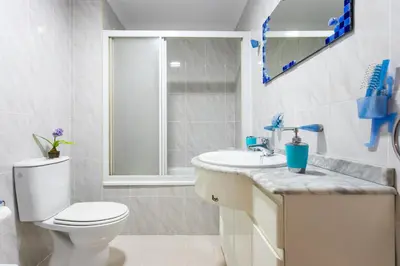 a white bathroom with a toilet and a sink at ApartUP Saplaya Harbour in Alboraya