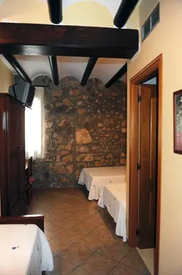 a room with two beds in a stone wall at Hotel Restaurant Verdià in Sueras