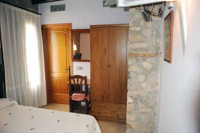 a bedroom with a bed and a wooden cabinet at Hotel Restaurant Verdià in Sueras