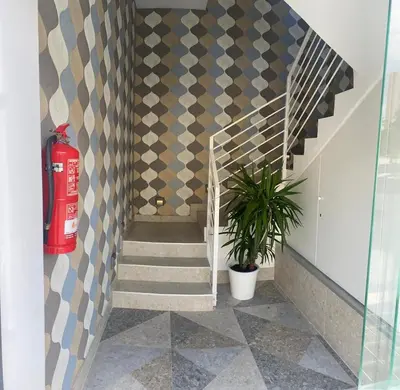 a hallway with a fire extinguisher and a staircase with a patterned wall at Nanit Valencia Hostel in Valencia