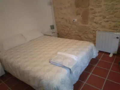 a bedroom with a bed and a stone wall at Casa Rural La Tia Rosa in Chulilla