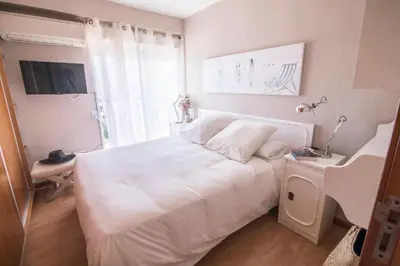 a white bedroom with a white bed and a window at Perfecto apto a orillas del mediterráneo / 4PAX in El Perellonet