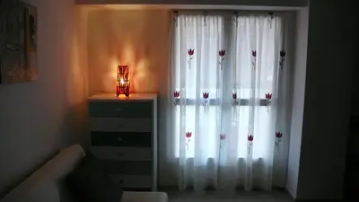 a bedroom with white curtains and a dresser with a lamp at Apartamento Portalet 7 in Benaguacil