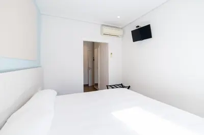 a bedroom with a white bed and a television at Hotel Alkazar in Valencia