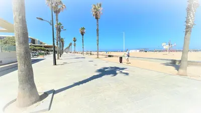 a person walking down a sidewalk next to the beach at BEACH VALENCIA LUXURY A40-35 Apartment with terrace and sea views in Valencia