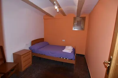 a small bedroom with a blue bed and orange walls at La Muralla Del Castillo in Chulilla