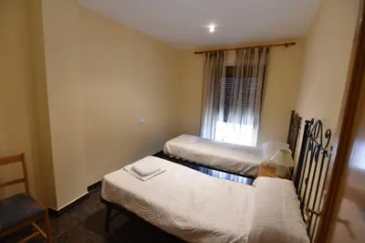 a room with three beds and a chair and a window at La Muralla Del Castillo in Chulilla