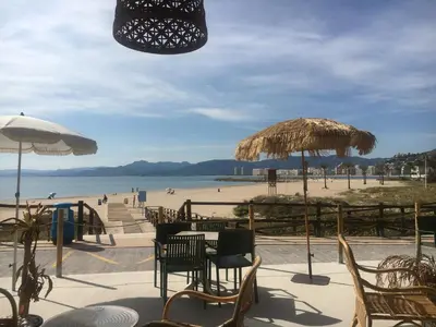 a patio with tables and chairs and a beach at Cap Blanc Penthouse in Cullera