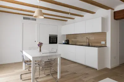 a kitchen with white cabinets and a white table at ApartUP L' Almoina in Valencia