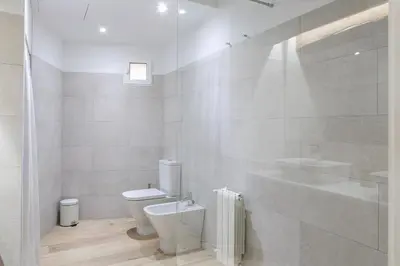 a white bathroom with a toilet and a sink at ApartUP L' Almoina in Valencia