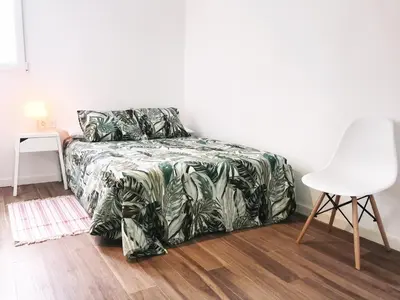 a bedroom with a bed and a white chair at Goya atico in Valencia
