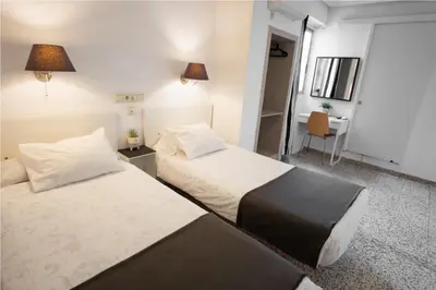 a hotel room with two beds and a desk at Hostal On Dormire Valencia in Valencia