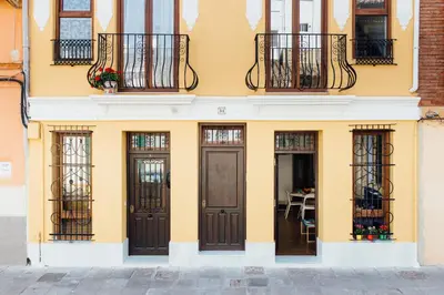 a yellow building with doors and windows and a table at Cabanyal Home in Valencia