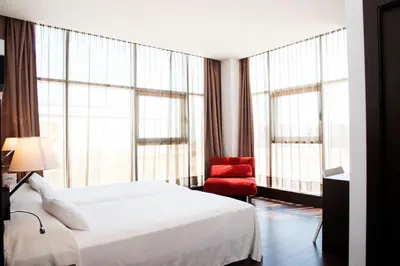 a hotel room with a bed and a red chair at Hotel Sercotel Plana Parc in Alquerías del Niño Perdido