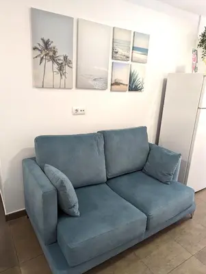 a blue couch in a room with pictures on the wall at Estudios en la playa in Valencia
