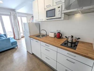 a kitchen with white cabinets and a sink and a refrigerator at Estudios en la playa in Valencia