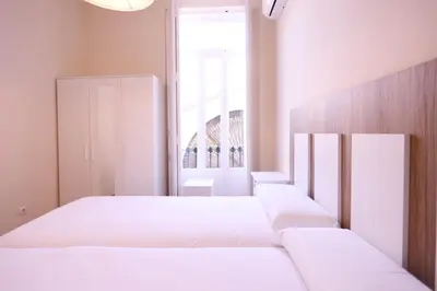 a bedroom with two white beds and a window at Apartamentos Dormavalencia in Valencia