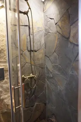 a shower in a bathroom with a stone wall at CASA DEL ARTE casa rural in Chulilla