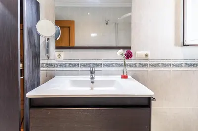 a bathroom with a sink and a vase of flowers at Casa los Buhos in Valencia