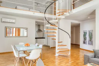 a spiral staircase in a living room with a table and chairs at Palau de Palomar - PalomarGroup in Valencia