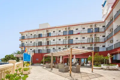 a hotel with chairs and a canopy in front of it at Hotel Sicania in Cullera
