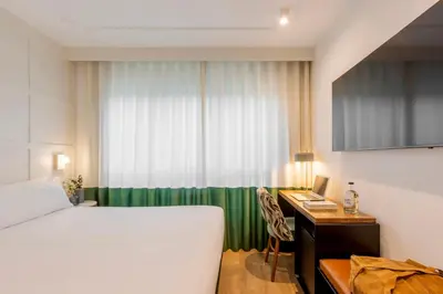 a hotel room with a bed and a desk and a window at Room Mate Cosmo - City Centre, Valencia in Valencia