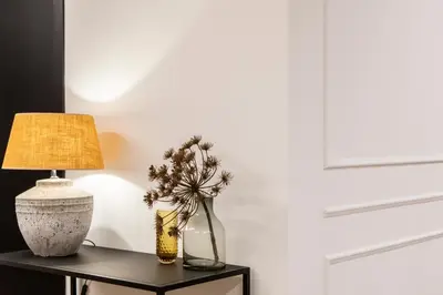 a table with a lamp and a vase with flowers at Blanq Comedias in Valencia