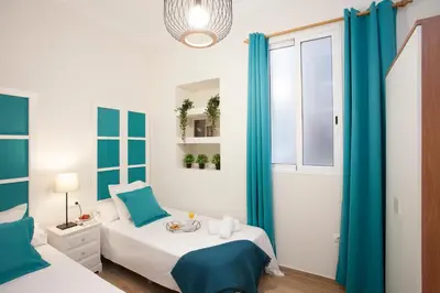 a bedroom with a bed and a window with blue curtains at SingularStays Seu Catedral in Valencia