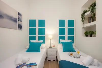 two beds in a white room with blue pillows at SingularStays Seu Catedral in Valencia